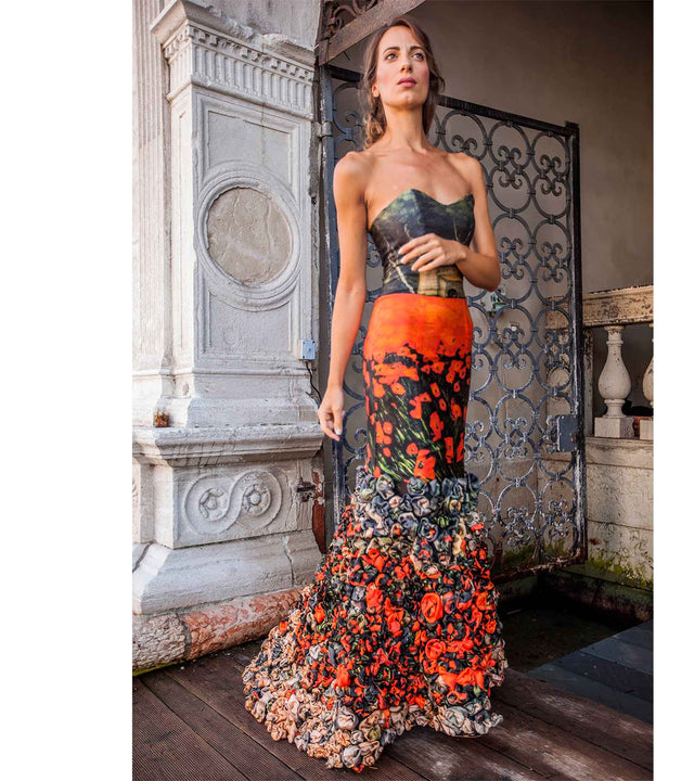 Model in a Vestilarte evening dress printed with red poppies, photographed in a historic Italian courtyard
